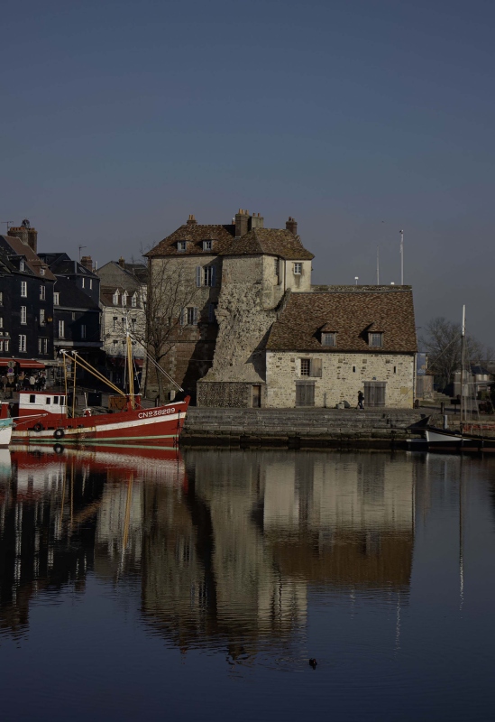 Quaint harbour with reflections and boats. A red boat on the left
